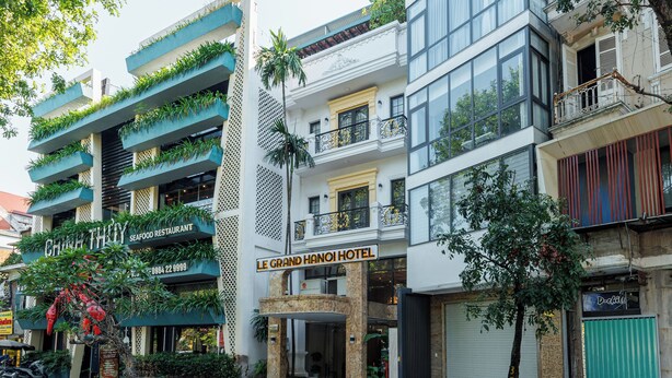 A multi-story hotel with balconies, a seafood restaurant, and a green gate.
