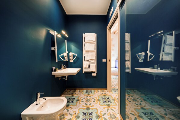 A bathroom with dark blue walls, a white sink, a bidet, and a towel rack. - Fortaleza Charme House (Syracuse)