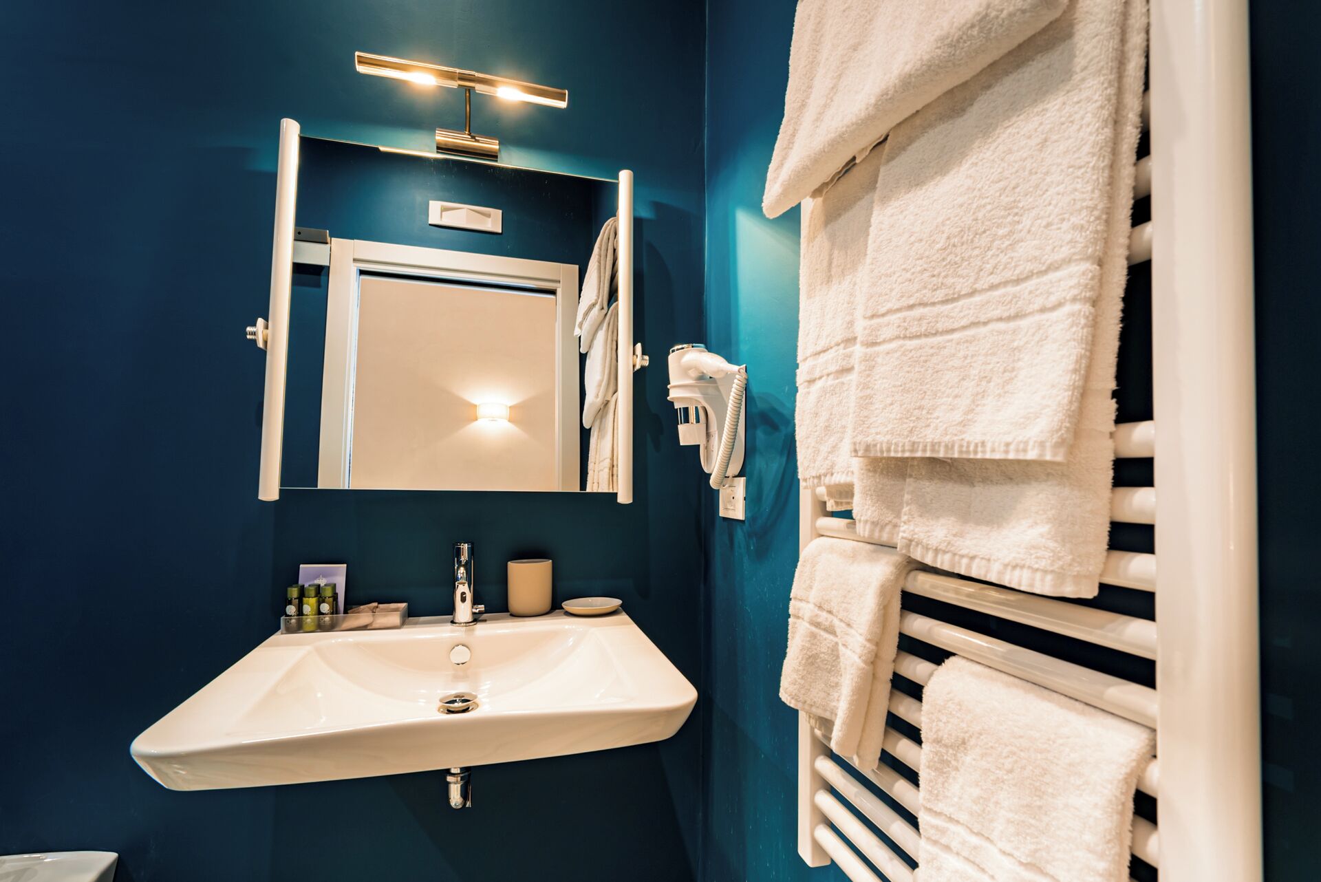 Une salle de bain avec un lavabo blanc, un miroir, un porte-serviettes et un sèche-serviettes.
