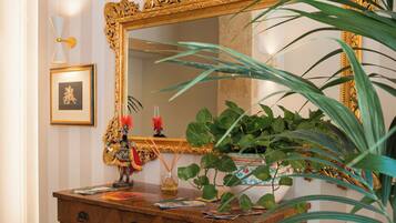A wooden dresser with a large ornate mirror, a framed picture, and a potted plant.