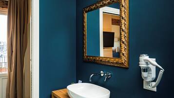 A bathroom with a white sink, wooden vanity, and a large mirror with a gold frame.