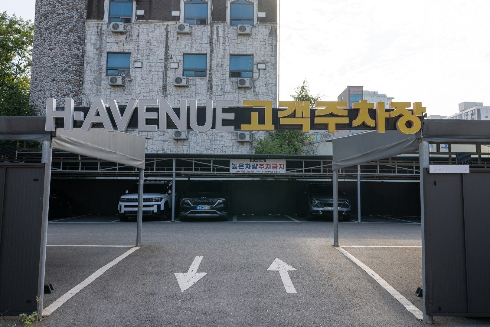 Una entrada cerrada a un estacionamiento con flechas direccionales en el suelo.