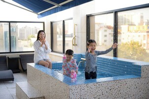 Una piscina interior moderna con zona de spa, ventanas amplias y vistas a la ciudad.
