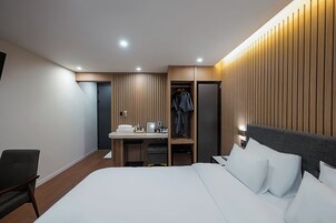 Una habitación de hotel moderna con cama, escritorio y armario.