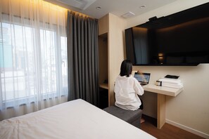 A hotel room with a bed, a desk with a laptop, a TV, and a window with curtains. - Mokpo H Avenue Hotel Peace Plaza (Mokpo)