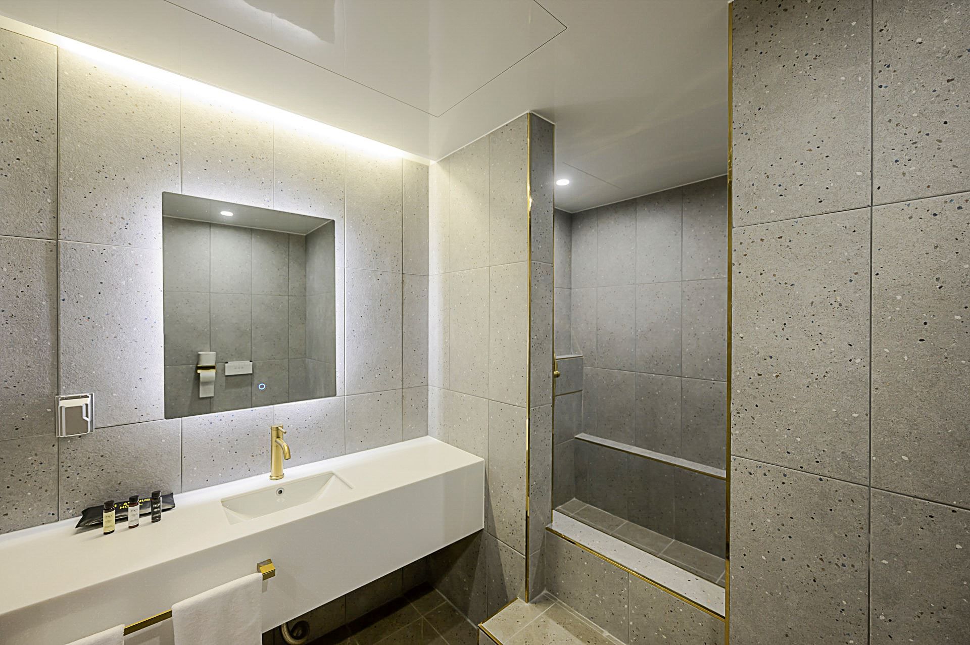 Un baño moderno con tocador blanco, un espejo grande y una zona de ducha.