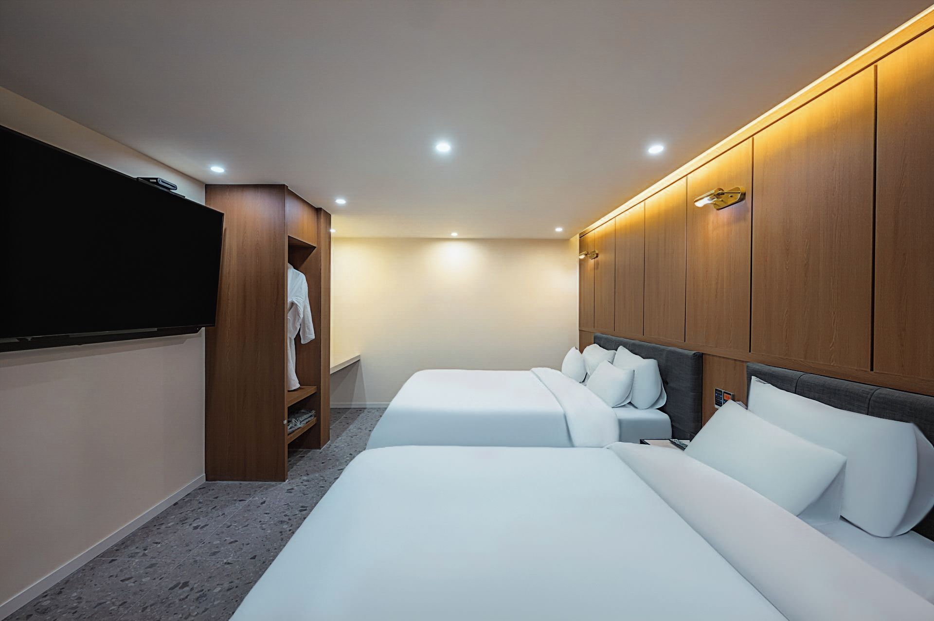 Habitación de hotel con dos camas, un armario y un televisor.
