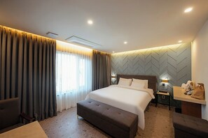 A hotel room with a large bed, a desk with a chair, a sofa, and a view of the outdoors. - Mokpo H Avenue Hotel Peace Plaza (Mokpo)