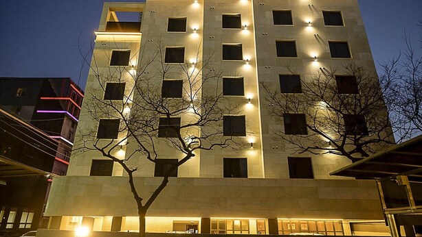Un hotel de varios pisos con ventanas iluminadas y una fachada plana.