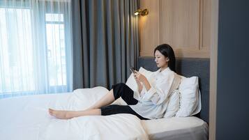 A person lying on a bed in a hotel room, reading a book.