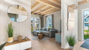 Un salon moderne avec un plafond en bois, un grand miroir rond, un canapé gris et une grande fenêtre.