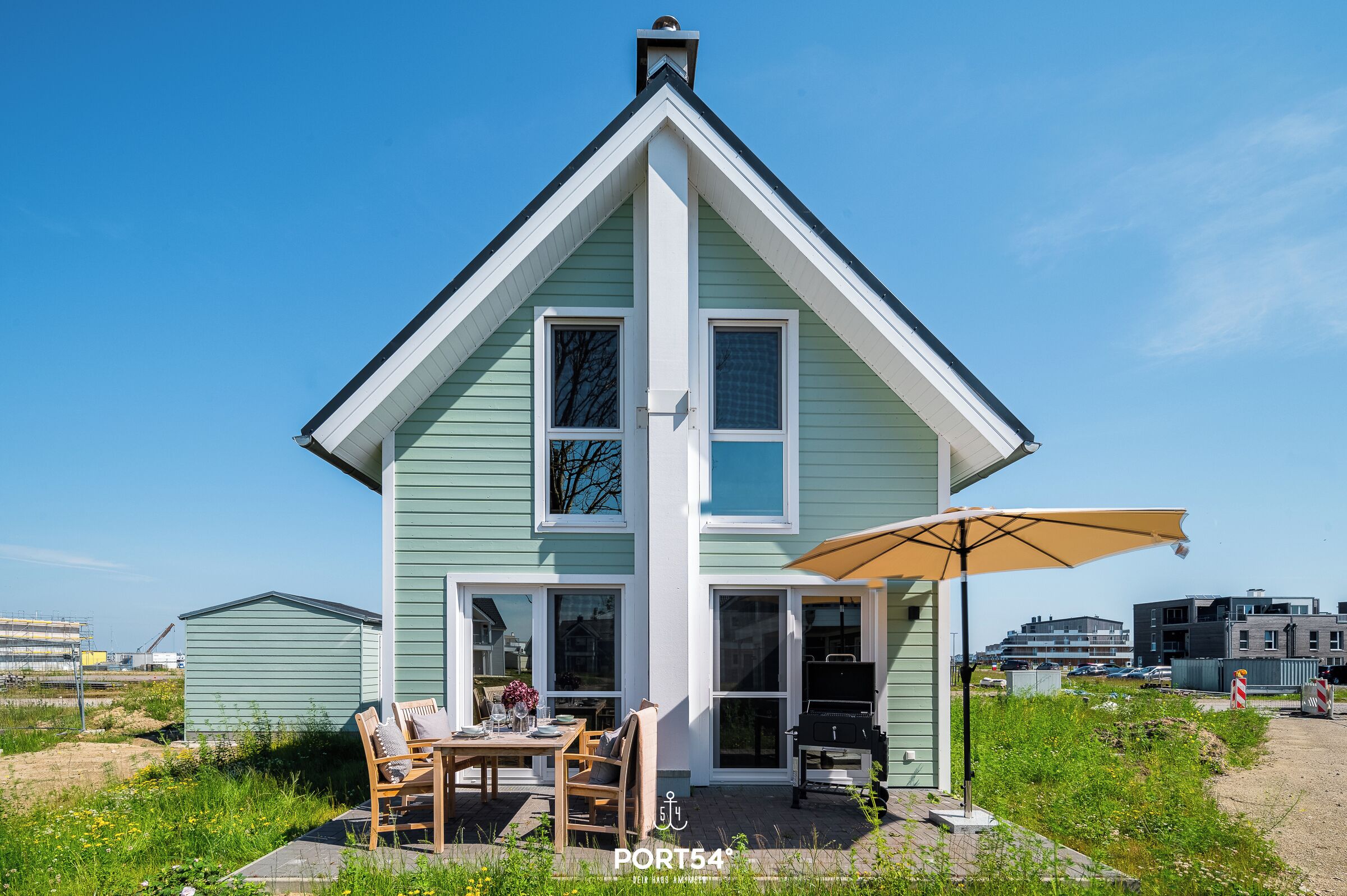 A house with a patio, a table, chairs, and a grill.