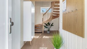 Un intérieur moderne avec un escalier en bois, une plante en pot et un panneau accroché au mur.