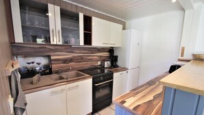 A modern kitchen with white cabinets, a wooden countertop, and a built-in oven.
