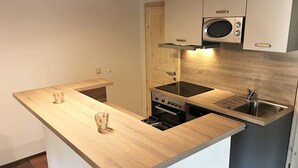 Kompakti keittiö, jossa on puinen keittiösaareke sekä sisäänrakennettu mikroaaltouuni, uuni ja pesuallas.