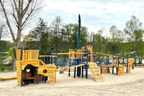 Un parque infantil con estructuras de madera para escalar y una zona de juegos con arena.