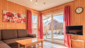 A cozy living room with a wooden floor, a brown sofa, a wooden coffee table, and a flat-screen TV on a wooden stand. - Möwe 35 - Kleines Gemütliches Ferienhaus im Ferienpark Mirow (Mirow)