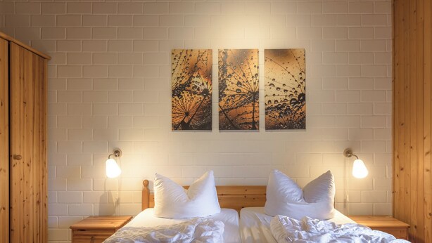 A double bed with white bedding, two bedside tables, and wall-mounted light fixtures.