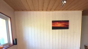 Ein rotes Ecksofa mit gelben Kissen in einem Raum mit Holzwandverkleidung und einer Deckenleuchte.