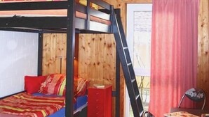 Ein Schlafraum mit Etagenbetten, einem Schreibtisch, einem Stuhl, Holzwänden und einem roten Teppich.