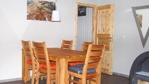 Ein Essbereich mit Holztisch und -stühlen, einer Pendelleuchte und einem Bild an der Wand.