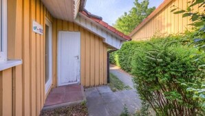 Ein gelbes Gebäude mit einer weißen Tür und einer kleinen Veranda.