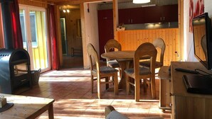 A cozy wooden interior with a dining area, a kitchen, and a fireplace. - Möwe 111 - Cozy vacation home in the vacation park Mirow (Mirow)