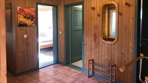 A wooden interior hallway with a door leading to a room, a metal rack, and a framed picture on the wall. - Möwe 111 - Cozy vacation home in the vacation park Mirow (Mirow)