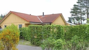 A yellow building with a red roof, surrounded by greenery. - Möwe 151 - Kleines Gemütliches Ferienhaus im Ferienpark Mirow (Mirow)
