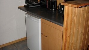A compact kitchen with a dishwasher, a coffee maker, and a toaster on the countertop. - Möwe 151 - Kleines Gemütliches Ferienhaus im Ferienpark Mirow (Mirow)