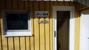 Un edificio amarillo con una ventana y una puerta. Un letrero sobre la puerta dice 'Ferienspark 154' y 'Bienvenido'.