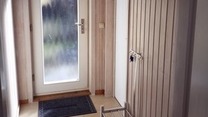 Una habitación con puerta de vidrio corredera, felpudo, estante metálico y pared de madera.