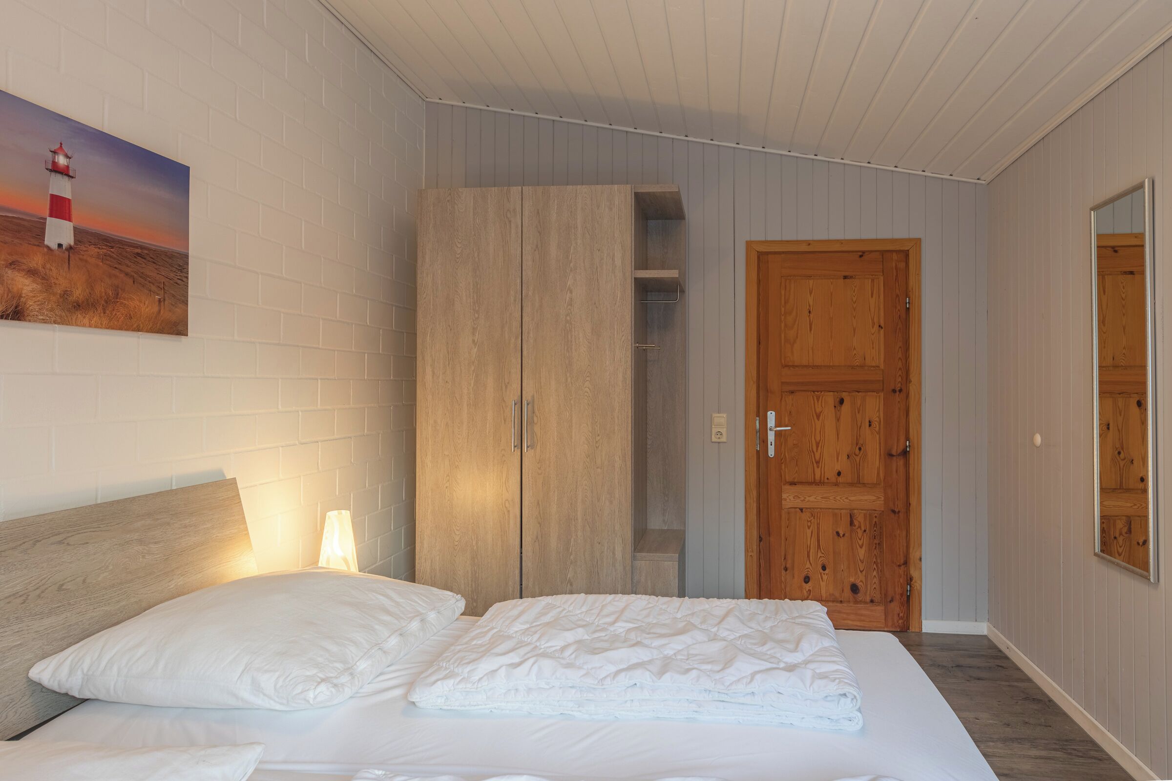 Ein Schlafzimmer mit Bett, Schrank, Tür und einem Bild an der Wand.