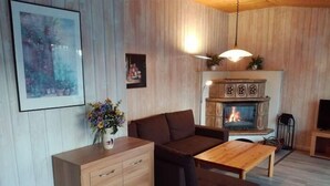Una sala de estar acogedora con un aparador de madera, un sofá, una mesa y una chimenea.