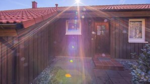 Una cabaña de madera con techo de tejas, un pequeño porche y una ventana.