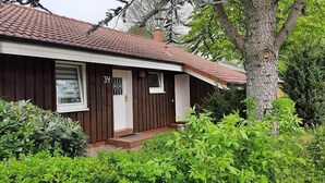 A single-story house with a brown exterior, a red-tiled roof, and a white door. - Milan 34 - Ferienbungalow auf Einer Ebene für 4 Personen (Mirow)