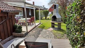 A patio area with a stone floor, a barbecue grill, and a table with chairs. - Milan 34 - Ferienbungalow auf Einer Ebene für 4 Personen (Mirow)