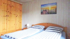Ein Zimmer mit einem Bett, einem Holzschrank und einem Bild an der Wand.