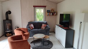 Ein Wohnzimmer mit einer Couch, einem Couchtisch, einem Kamin, einem Fernseher und einem Bücherregal.