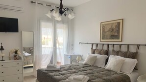 A neatly arranged bedroom with a large bed, bedside tables, a dresser, and a television. - Villa Serendipity Terrasini (Terrasini)