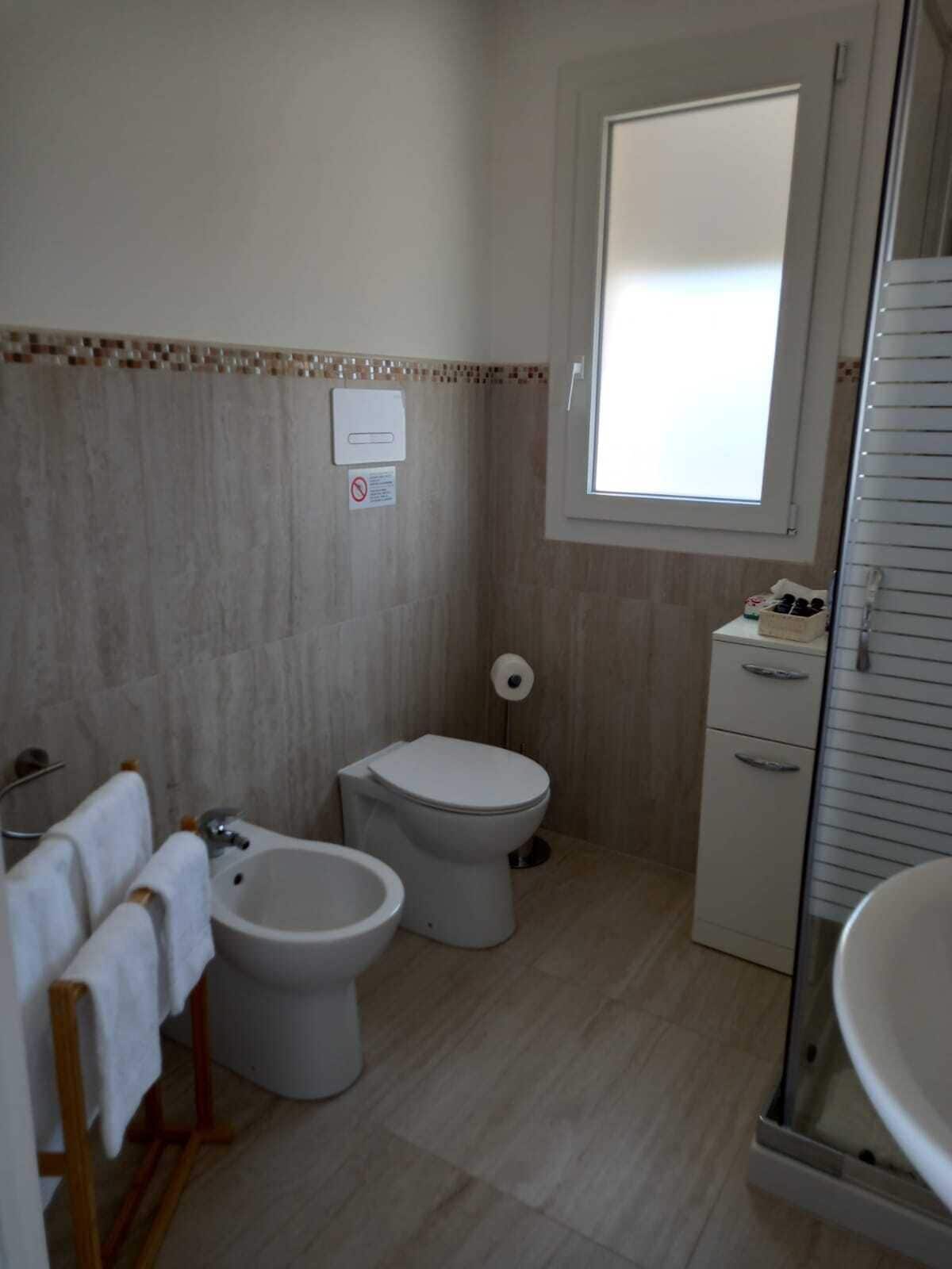 A bathroom with a bidet, toilet, and sink.