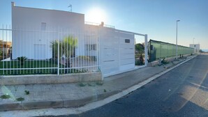 A modern building with a white exterior, a gated entrance, and a paved sidewalk. - Villa Serendipity Terrasini (Terrasini)