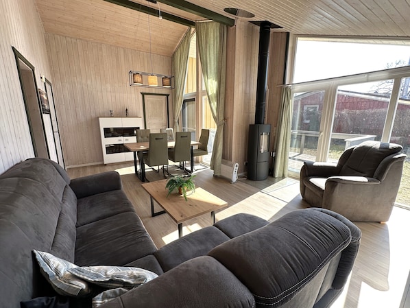 A modern living room with a sofa, chairs, a coffee table, a fireplace, and a dining area.