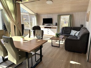 A modern living room with a dining area, a sofa, and a TV.
