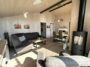 A cozy living room with a sofa, a coffee table, a fireplace, and a dining area.