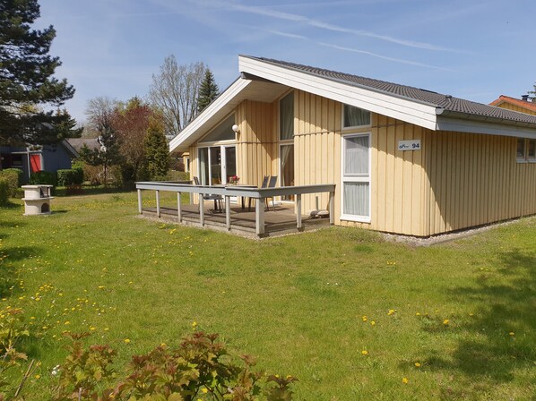 Eine Holzhütte mit einer Terrasse, einem überdachten Sitzbereich im Freien und einem Schild mit der Adresse.