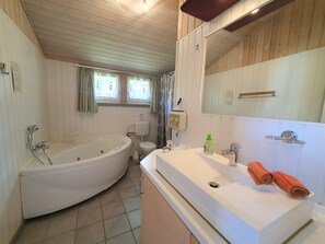 Ein Badezimmer mit Badewanne, Toilette, Waschbecken und Spiegel.