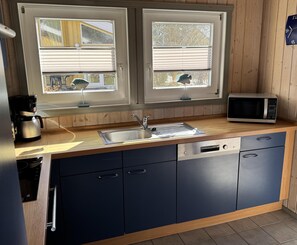 Cocina con pileta de acero inoxidable, microondas y cafetera.