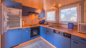 A compact kitchen with blue cabinets, a stove, a dishwasher, and a microwave.