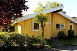 Simple, single-story residence with a sloped roof and a small tree in the front yard.